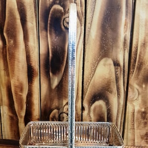 May include: Silver metal wire basket with a handle. The basket has a rectangular shape and a decorative design.