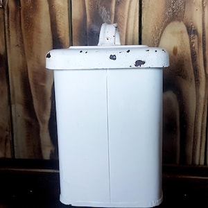 Peut inclure: Boîte rectangulaire en métal blanc avec une poignée sur le dessus. La boîte a un aspect vieilli et vintage avec des taches de rouille.