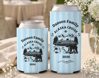 May include: Two light blue and white striped can coolers featuring a black graphic of a cruise ship, mountains, a bear, and the text Danson Family ALASKA CRUISE 2026. The coolers are designed to hold standard beverage cans securely.