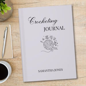 May include: A white crocheting journal with the title "Crocheting JOURNAL" in black script and block letters. The cover features a line drawing of a yarn ball, crochet hook, and floral elements. The name "SAMANTHA JONES" is printed at the bottom.