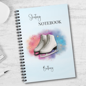 Könnte beinhalten: Ein spiralgebundenes Notizbuch mit den Worten "Skating NOTEBOOK" in schwarzer Schrift. Das Cover zeigt ein Aquarelldesign mit weißen Schlittschuhen und dem Namen "Brittany" in Schrift.