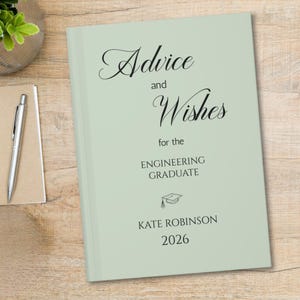 May include: A sage green hardcover book with black text that reads Advice and Wishes for the ENGINEERING GRADUATE, featuring a small graduation cap icon, the name KATE ROBINSON, and the year 2026 printed on the front cover in a clean font.