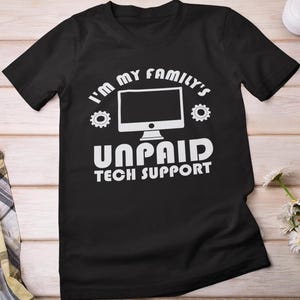 May include: Black t-shirt with white text: "I'm my family's unpaid tech support." The design features a computer monitor graphic and gear icons. A casual, comfortable tee.