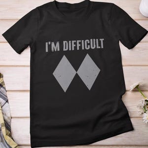 May include: Black t-shirt with the text "I'M DIFFICULT" and two gray diamond shapes.