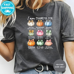 May include: Dark gray t-shirt with the text "I am THANKFUL FOR" and colorful pumpkin illustrations. Each pumpkin represents a different blessing, with corresponding Bible verses. The shirt is made of a soft material.