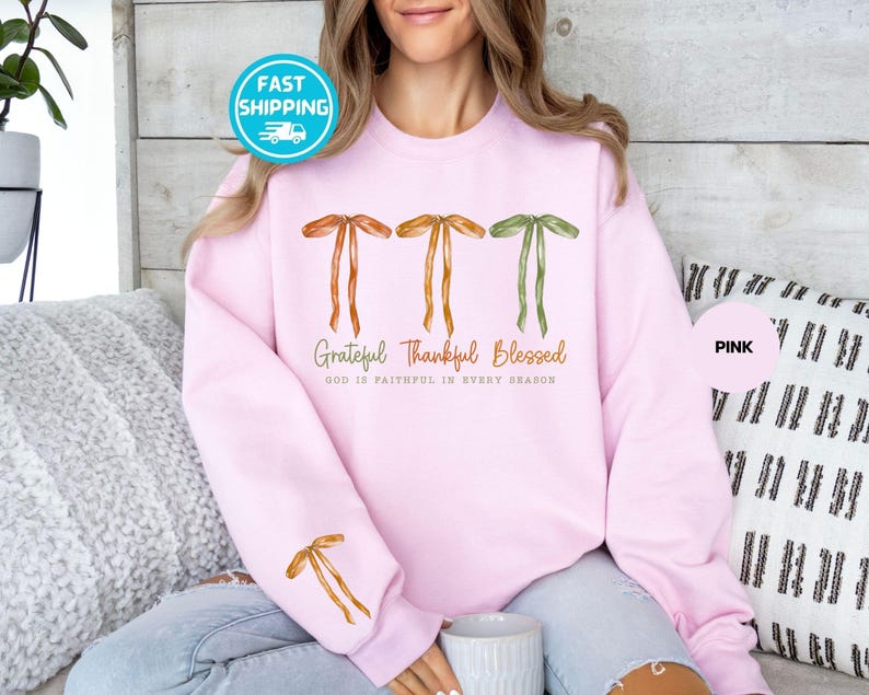 Pu&ograve; includere: Una felpa rosa chiaro con le parole "Grateful Thankful Blessed" e la frase "God is faithful in every season" stampate sul davanti. La felpa presenta tre disegni a fiocco e un fiocco sulla manica sinistra.