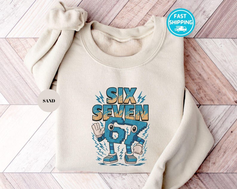 May include: A sand-colored sweatshirt with the words "SIX SEVEN" in a retro font. The number "67" is designed as a cartoon character with arms, legs, and shoes. The design is in shades of blue, teal, and orange. A "Fast Shipping" sticker is visible.