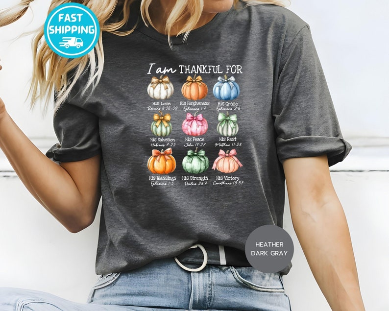 May include: Dark gray t-shirt with the text "I am THANKFUL FOR" and colorful pumpkin illustrations. Each pumpkin represents a different blessing, with corresponding Bible verses. The shirt is made of a soft material.