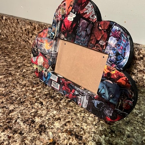 May include: A cloud-shaped picture frame made of cardboard and covered in a collage of comic book pages featuring superheroes like Spider-Man, Iron Man, and Captain America.
