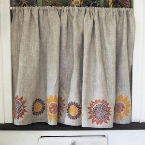 May include: A beige linen valance with a row of brown, orange, and yellow sunflower designs along the bottom edge.