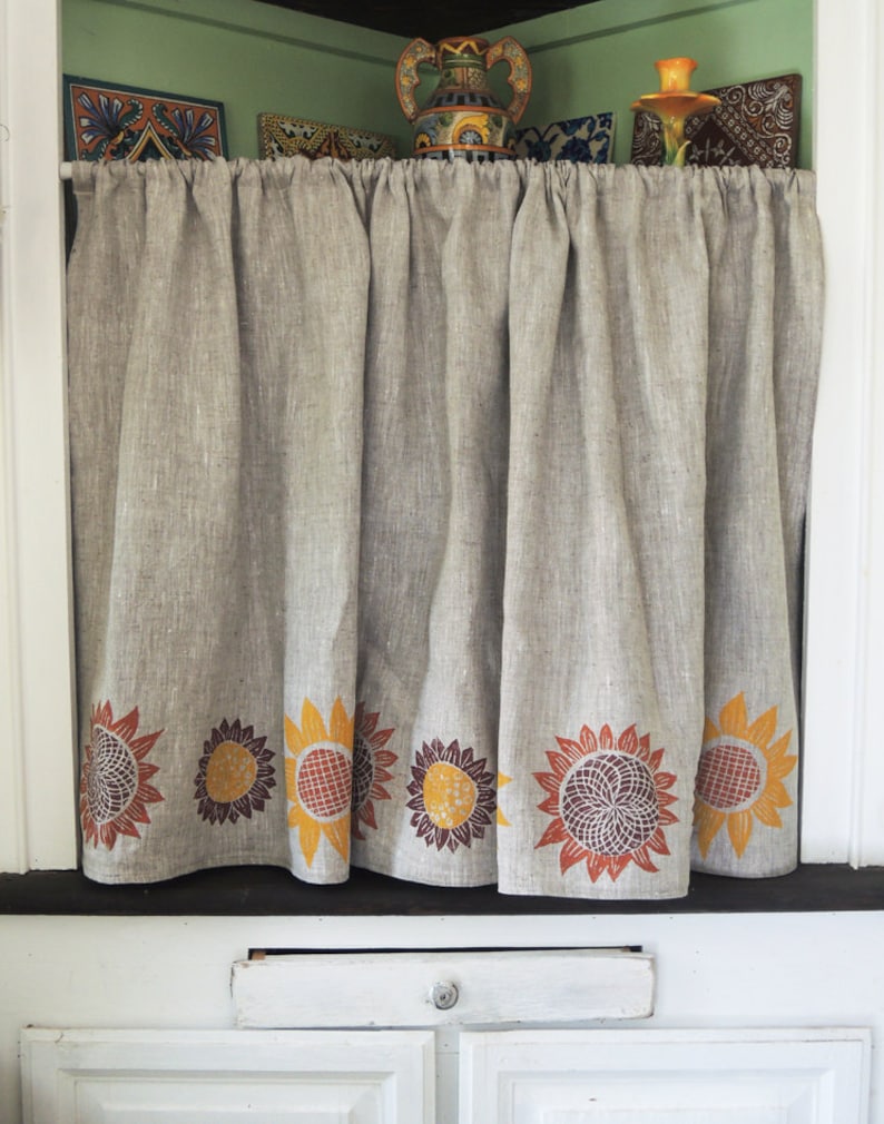 May include: A beige linen valance with a row of brown, orange, and yellow sunflower designs along the bottom edge.