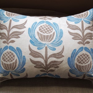 May include: A white pillow with a blue and brown floral pattern. The pillow has a rectangular shape and is made of a soft, textured fabric.