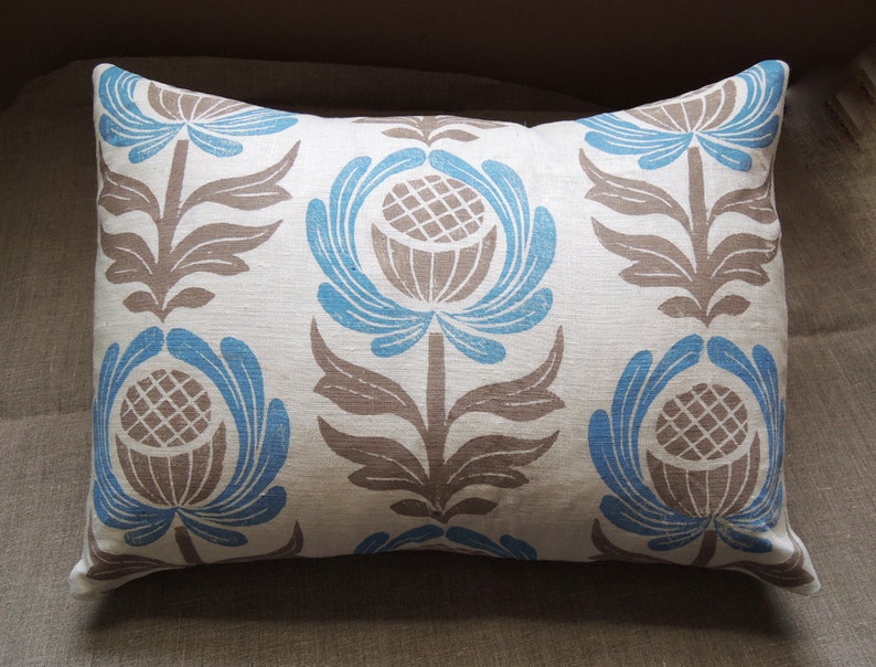 May include: A white pillow with a blue and brown floral pattern. The pillow has a rectangular shape and is made of a soft, textured fabric.