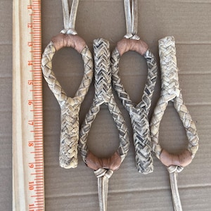 May include: Four braided leather rope halters with brown leather accents. The halters are approximately 6 inches long and are displayed against a brown background.