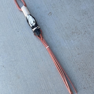 May include: A black and white leather braided whip with a cowhide handle. The whip is approximately 40 inches long.