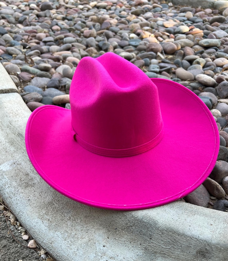 Puede incluir: Un sombrero de vaquero fucsia vibrante con ala ancha. El sombrero est&aacute; hecho de un material suave y presenta una forma de corona cl&aacute;sica. Un accesorio de moda audaz.