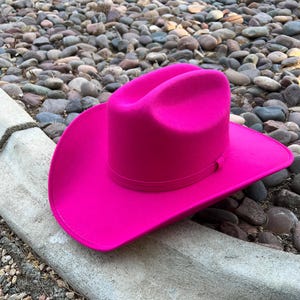 Puede incluir: Un sombrero de vaquero fucsia vibrante. El sombrero presenta un dise&ntilde;o cl&aacute;sico con ala ancha y corona estructurada. Fabricado con un material similar al fieltro, a&ntilde;ade un toque de color a cualquier atuendo.