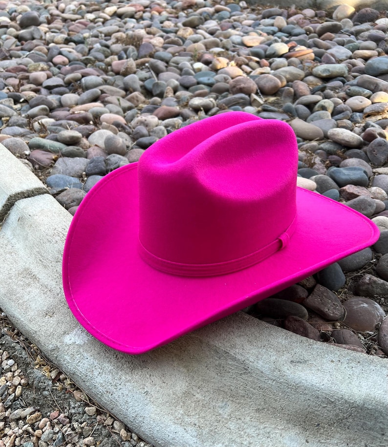 Puede incluir: Un sombrero de vaquero fucsia vibrante. El sombrero presenta un dise&ntilde;o cl&aacute;sico con ala ancha y corona estructurada. Fabricado con un material similar al fieltro, a&ntilde;ade un toque de color a cualquier atuendo.