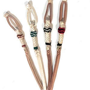 May include: Four white leather braided lanyards with different colored tassels. The tassels are red and white, green and white, black and white, and red and black.