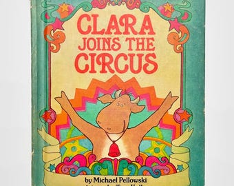 May include: A vintage children's book cover with a colorful psychedelic design. The title is "Clara Joins the Circus" with a cartoon cow wearing a bell around its neck. The book is by Michael Pelloswki with pictures by True Kelley.