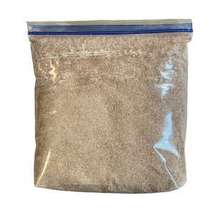 May include: A clear plastic resealable bag filled with a light brown, fine-grained powder.