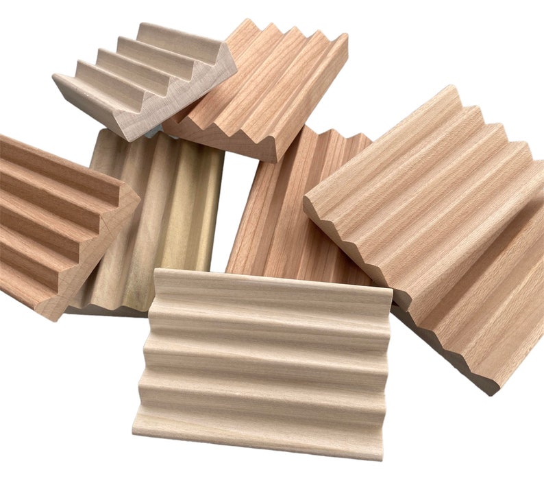 May include: A collection of wooden soap dishes in various shapes and shades of light brown. The dishes have a ridged design to allow for drainage. The wood grain is visible, and the dishes are arranged against a white background.