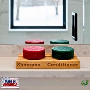 May include: A wooden shampoo and conditioner holder with two solid shampoo and conditioner bars. The shampoo bar is red, and the conditioner bar is green. The holder is engraved with the words "Shampoo" and "Conditioner".
