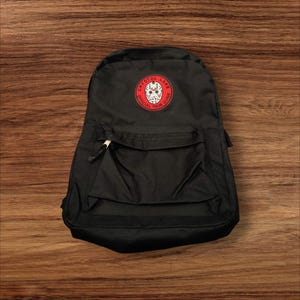 May include: Black backpack with a red and white patch that says "Crystal Lake Official Town Guide" and has a hockey mask graphic.