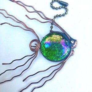 May include: A green glass fish with iridescent accents and glitter, attached to a copper wire with a chain and a key ring.