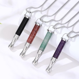 Peut inclure: Quatre pendentifs cylindriques sur des chaînes en argent. Chaque pendentif présente un embout et un capuchon en métal argenté avec un corps central en pierre de couleur noire, brun rougeâtre, vert clair ou violet foncé, fixé par un anneau.