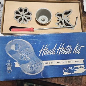 May include: Vintage Handi Hostess Kit for Waf-lette and Patty Shell molds. The kit includes a metal handle with a red grip, three metal molds, and a blue box with the kit's name and illustrations.