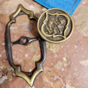 May include: A white ceramic mug with a black handle and the text "But First, Coffee" in a black, handwritten-style font. The mug is on a white surface.