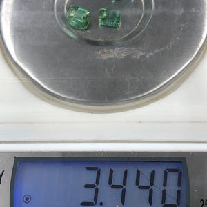 May include: Three faceted, emerald-green gemstones are displayed on a silver scale. The digital display shows a weight of 3.440 ct. The gemstones are rectangular and appear to be of similar size and shape.