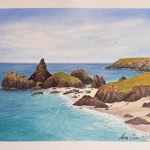 May include: Watercolour painting of a coastal scene with turquoise sea, sandy beach, and rocky cliffs. The artwork depicts a tranquil scene with a blue sky and birds. Signed "James Moore 10/25".