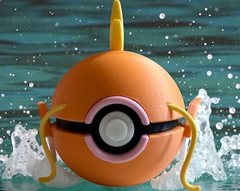 May include: An orange, spherical figure with yellow and pink accents, floating in water. The figure has a central black band with a white and pink circular design. Yellow tendrils extend from the sides, and a yellow fin rises from the top.