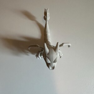 Peut inclure: Figurine de scorpion gris clair, stylis&eacute;e, avec un corps segment&eacute; d&eacute;taill&eacute;, des pinces et une queue incurv&eacute;e. Le scorpion a une t&ecirc;te d&eacute;taill&eacute;e avec de grands yeux ovales et deux cornes. La figurine est pos&eacute;e sur un fond blanc uni.