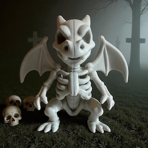 Peut inclure: Une figurine de gargouille blanche stylis&eacute;e avec un design squelettique, des ailes de chauve-souris et une expression mena&ccedil;ante. Trois petits cr&acirc;nes sont positionn&eacute;s &agrave; gauche de la gargouille. L'arri&egrave;re-plan pr&eacute;sente une sc&egrave;ne de cimeti&egrave;re avec des pierres tombales et une atmosph&egrave;re brumeuse.