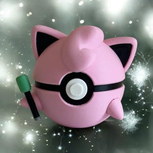 May include: A pink and black Pokemon figure of Jigglypuff holding a green and black microphone. The figure is a 3D print.