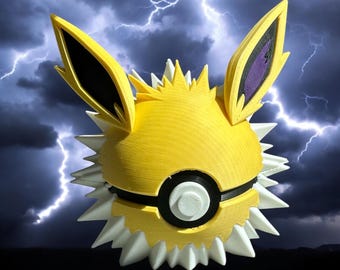 Könnte beinhalten: Eine gelbe und weiße 3D-gedruckte Pokémon-Figur eines Jolteon, ein Pokémon vom Typ Elektro, mit schwarzen Ohren und violetten Akzenten. Die Figur ist in Kugelform mit herausstehenden Ohren dargestellt.