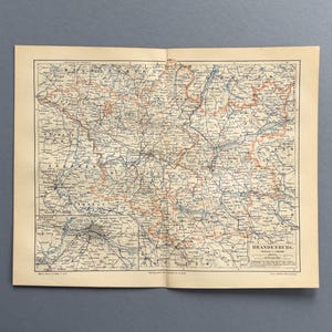 May include: A vintage paper map of the Brandenburg region in Germany, featuring detailed black lines for roads and railways, orange borders for administrative districts, and a smaller inset map of Berlin and its surrounding areas in the bottom left corner.