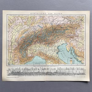 Op de afbeelding: Antieke kaartafdruk met de titel "Einteilung Der Alpen" met een gedetailleerd topografisch beeld van de Alpen. De kaart gebruikt verschillende kleuren om het terrein weer te geven, met tekst in het Duits. Onderaan is een dwarsdoorsnede van de bergen te zien.