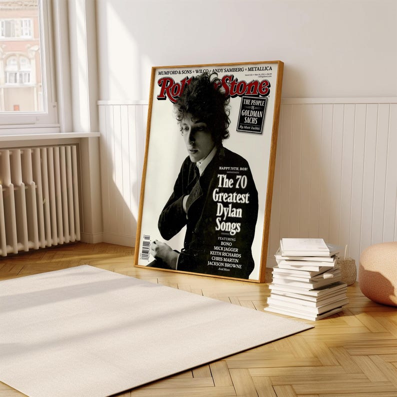 May include: A magazine cover featuring a black and white photo of Bob Dylan. The magazine is titled "Rolling Stone" and the headline reads "The 70 Greatest Dylan Songs".