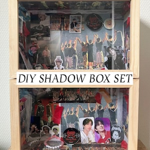 Op de afbeelding: Een houten DIY shadow box set met een heldere glazen voorkant. De doos is gevuld met diverse afbeeldingen, stickers en memorabilia. De tekst "DIY SHADOW BOX SET" staat op de voorkant van de doos. De doos heeft een lichtbruine kleur.
