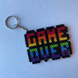 May include: A black keychain with the words "GAME OVER" spelled out in colorful beads. The letters are in a rainbow gradient, and the keychain has a silver ring and chain.