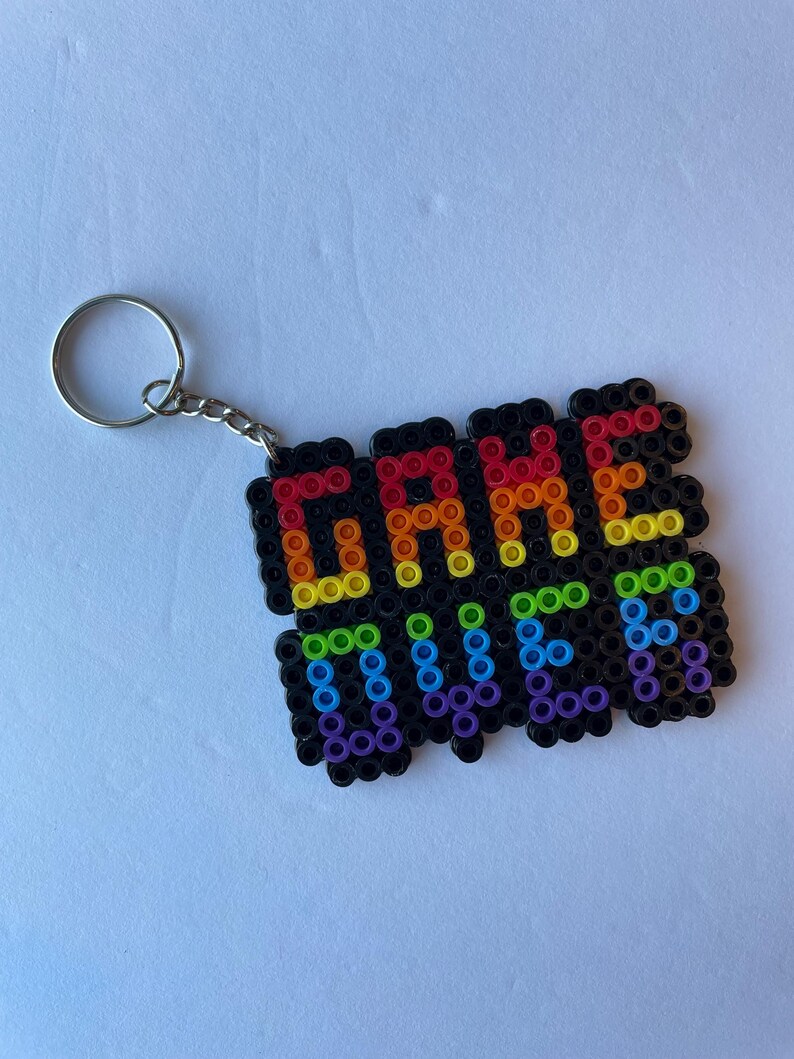 May include: A black keychain with the words "GAME OVER" spelled out in colorful beads. The letters are in a rainbow gradient, and the keychain has a silver ring and chain.