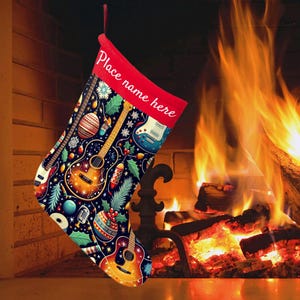 May include: A Christmas stocking with a red cuff that reads "Place name here." The stocking is decorated with guitars, ornaments, snowflakes, and holly on a dark blue background. A red loop hangs from the top.