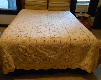 May include: A crocheted bedspread in a cream color with a square pattern. The bedspread is on a bed with two pillows.