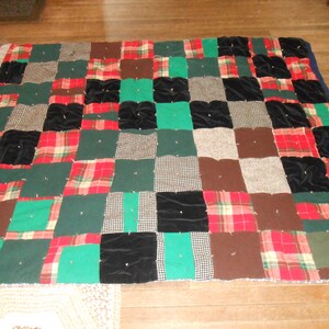 May include: A patchwork quilt made from various fabrics, including plaid, velvet, and houndstooth. The quilt is a mix of red, green, black, brown, and white.