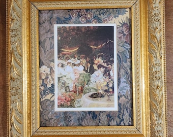Könnte beinhalten: Ein gerahmter Druck eines gesellschaftlichen Treffens mit einem goldfarbenen, verzierten Rahmen. Der Druck zeigt eine Gruppe von Menschen an Tischen, vor einem floralen Tapetenhintergrund. Der Rahmen hat ein detailliertes, strukturiertes Design.