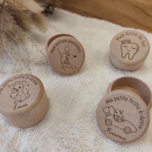 Peut inclure: Quatre boîtes rondes en bois clair avec couvercles, chacune présentant des illustrations gravées au laser de souris ou d'une dent. Les couvercles portent des textes français dont 'Mes petites quenottes', 'Mes dents de lait' et 'Ma petite boîte à dents'.